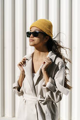 Elegante Frau mit Sonnenbrille und Jacke vor einer Wand - EGAF02519