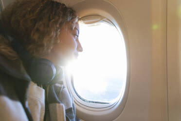 Junge Frau schaut aus dem Flugzeugfenster - MRAF00801