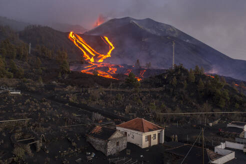 Luftaufnahme eines Hauses mit dem Vulkan Cumbre Vieja im Hintergrund, ein Vulkan während eines Ausbruchs in der Nähe der Stadt El Paraiso, Las Manchas, Insel La Palma, Kanarische Inseln, Spanien. - AAEF13601