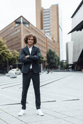 Confident businessman with arms crossed standing at city square - GUSF06688