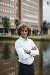 Businessman with arms crossed at riverbank - GUSF06702