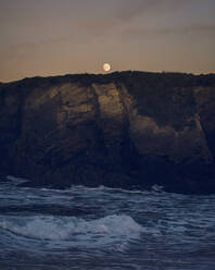 Der Mond leuchtet in der Abenddämmerung über den Klippen von Sartana Beach - RAEF02454