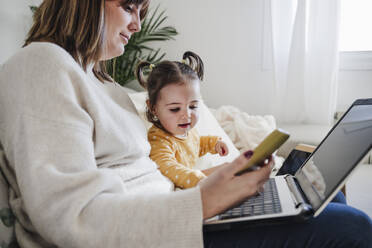 Mother using laptop with daughter at home - EBBF05100