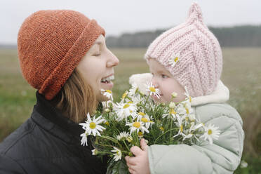 Glückliche Mutter mit ihrem kleinen Mädchen und Kamillenblüten - EYAF01821