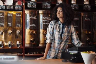 Contemplative businesswoman standing in coffee roastery - KNSF09187