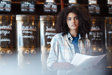 Serious owner holding document at coffee roastery - KNSF09203