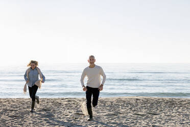 Mann und Frau laufen auf Sand am Strand - EIF02561