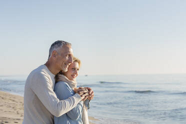 Mann umarmt Frau am Strand - EIF02592