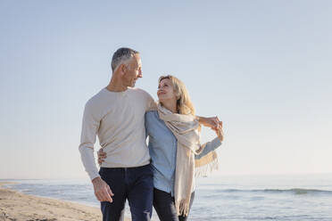 Woman with scarf looking at husband at beach - EIF02594