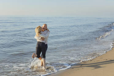 Mann spielt mit Frau im Wasser am Strand - EIF02604