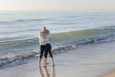 Unbeschwertes Paar umarmt sich in der Nähe von Meeresufer am Strand - EIF02606