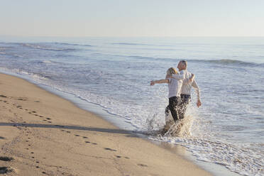 Paar bespritzt sich gegenseitig am Strand mit Wasser - EIF02607