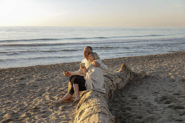 Mann mit Frau genießt Sonnenuntergang am Strand - EIF02621