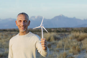 Smiling man holding wind turbine model - EIF02628