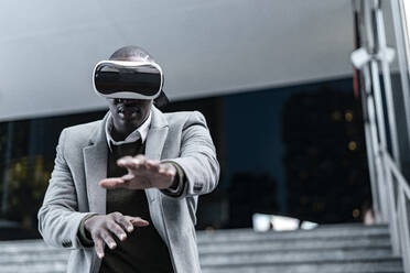 Businessman gesturing wearing virtual reality headset in subway at night - GIOF14457