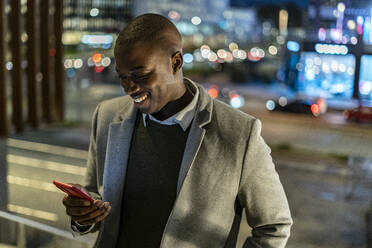 Geschäftsmann benutzt Smartphone in der Stadt bei Nacht - GIOF14469