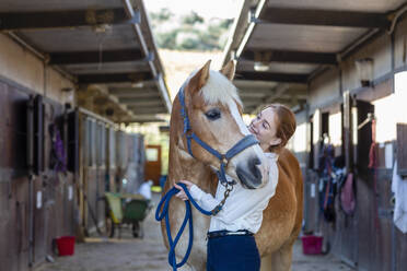 Frau kümmert sich um ein Pferd im Stall - EIF02644