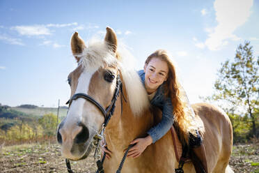 Lächelnde Frau auf Pferd sitzend auf einer Wiese am Wochenende - EIF02651