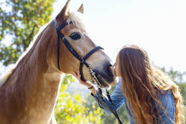 Redhead woman kissing horse at meadow - EIF02655