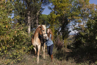 Junge Frau mit Pferd auf einer Wiese an einem sonnigen Tag am Wochenende - EIF02657
