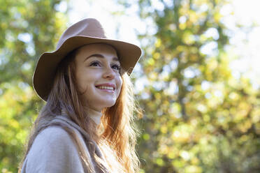 Lächelnde nachdenkliche Frau mit Hut im Wald - EIF02678