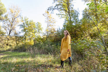 Young woman wrapped in blanket walking in forest - EIF02685