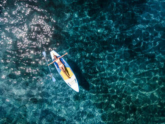 Frau auf Paddleboard im Meer liegend im Urlaub - HMEF01335