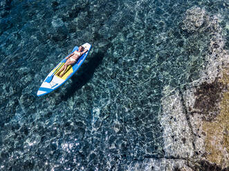 Reife Frau im Bikini auf Paddleboard im Meer liegend im Urlaub - HMEF01337