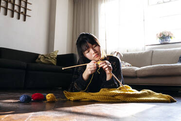 Woman knitting and relaxing on floor at home - ASGF01941