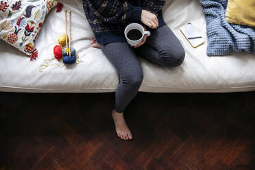 Frau hält Kaffeetasse auf Sofa - ASGF01946