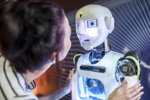 Tech developer looking at human robot in workshop - WESTF24765