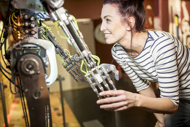 Smiling technician shaking hand with human robot at workshop - WESTF24809