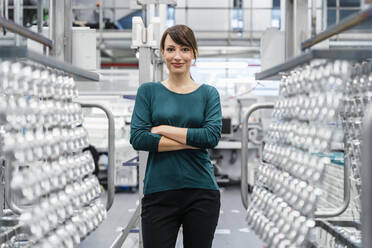 Businesswoman standing with arms crossed at automated factory - DIGF17067