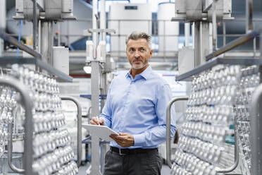 Thoughtful businessman holding tablet PC at industry - DIGF17069