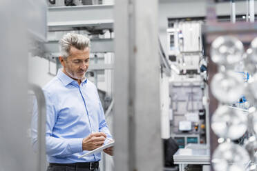 Businessman using tablet PC at automated factory - DIGF17075