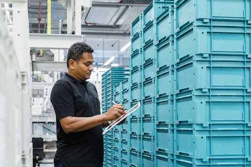 Lagerarbeiter mit Tablet-PC inmitten von Containern in der Industrie - DIGF17092