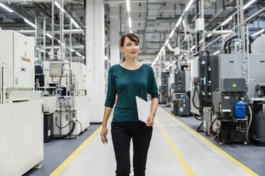 Lächelnde Geschäftsfrau mit Tablet-PC in automatisierter Fabrik - DIGF17118