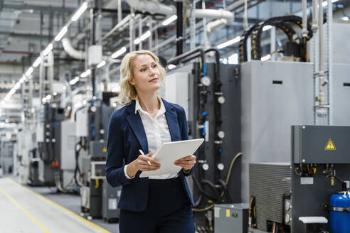 Businesswoman holding tablet PC in electrical industry - DIGF17120