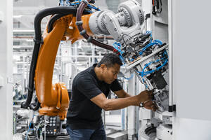 Engineer examining robotic arm in factory - DIGF17134