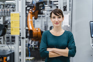 Smiling businesswoman with arms crossed at industry - DIGF17149