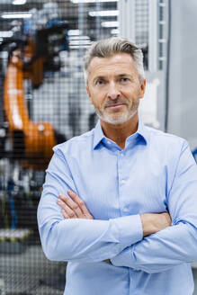 Confident businessman with arms crossed at industry - DIGF17151