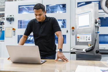 Wartungsingenieur mit Blick auf den Laptop in einer automatisierten Fabrik - DIGF17159