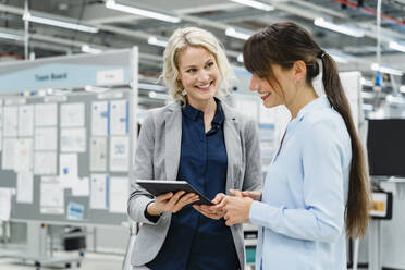 Smiling businesswoman working with colleague in modern factory - DIGF17174