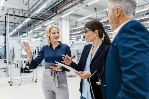 Geschäftsfrauen im Gespräch mit einem Geschäftsmann in einer automatisierten Fabrik - DIGF17212