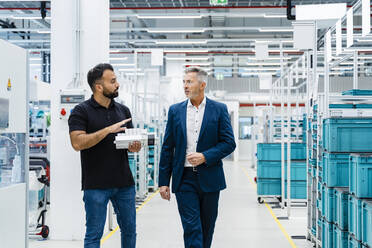 Businessman explaining engineer over electrical equipment at factory - DIGF17222