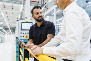 Businessman holding tablet PC with engineer at automated factory - DIGF17229