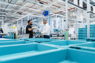 Coworkers having discussion by blue crates at factory production line - DIGF17246