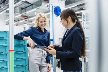 Smiling businesswoman working with colleague at industry - DIGF17248