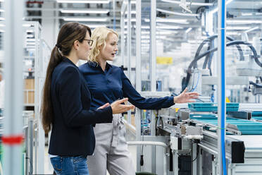 Businesswomen discussing over production line at factory - DIGF17251