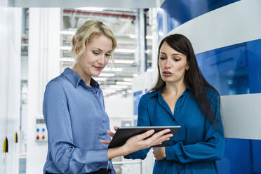 Coworkers discussing over tablet PC at automated industry - DIGF17279